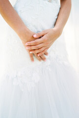 Obraz na płótnie Canvas Bride folded her hands on the hem of her wedding dress. Close-up