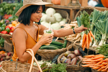 Vegetables, market and black woman shopping for grocery, natural and vegan food at small business. Farm supplier, carrot and young person or customer with basket for retail product, nutrition or diet - obrazy, fototapety, plakaty