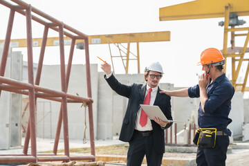 Male manager and foreman builder discussing precast concrete wall structure quality at construction site. Group of construction workers working at construction site