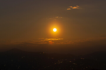 Rise of the orange moon, also known as the harvest moon or the hunter's moon, over the night sky at Sikkim, India. Moon orange due to atmosphere.