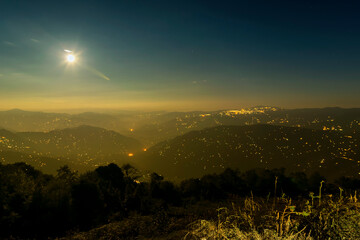 Pearls of light of Queen of Hills, Darjeeling town, at night at far right. Full moon on the night sky shows of mountains of Eastern Himalays with ridges and localities of Sikkim, West Bengal, India.