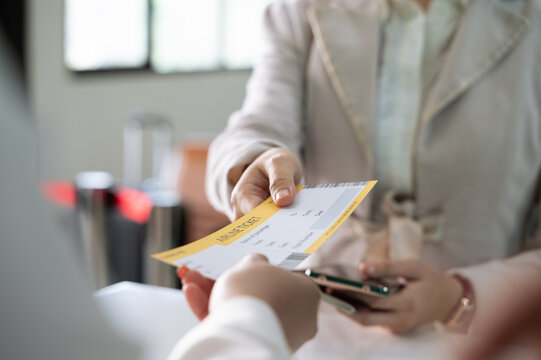 Businesswoman giving boarding pass to airlines ground attendant at airport departure gate