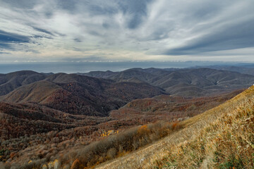 Mountain landscape with beautiful Caucasian nature. View of the mountain range under a cloudy sky. Panoramic view of the Caucasus mountains. Landscape of a mountain range on an autumn morning. 