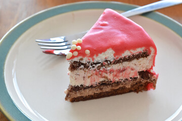 Strawberry and chocolate ice cream cake with a fork on a plate.