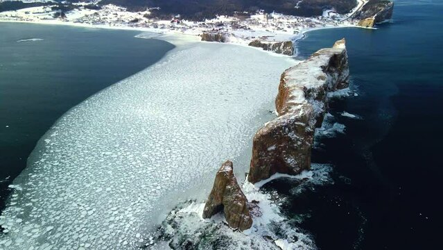 aerial view of Percé rock in the winter with ice on the ocean.
