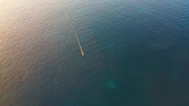 Aerial View Of Person Surfing Across Waters Off Cala Escondida Coastline On Electric Surfboards. Locked Off, High Angle