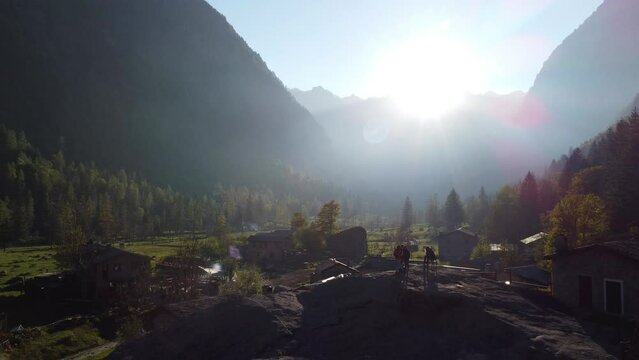 Val di mello in Sondrio, Italy, old houses and vegetation, mountains and between them the sun shining. Aerial cinematic shot .