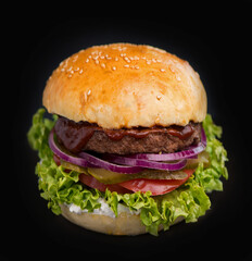 Close-up of a delicious fresh homemade burger with lettuce, cheese, onion and tomato on a rustic wooden board on a dark background