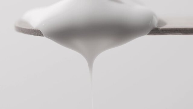 Cosmetic cream falls from a wooden spatula close-up. The texture of a beauty product for hair and skin care.