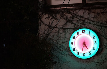 Lighted wall clock hanging on the wall of a building at night