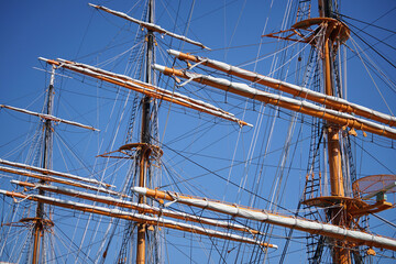 Mast of a sailing ship moored in the harbor on a clear blue sky day