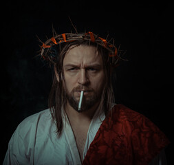 Jesus Christ smokes a cigarette wearing a crown of thorns and white chiton toga cape himation suffering for mankind's sins in artistic portrait