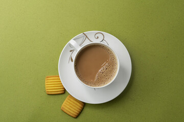 Cup of tea with egg and milk cookies isolated on green background