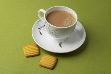 Cup of tea with egg and milk cookies isolated on green background