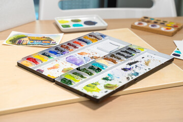 Colorful watercolor palette on table with watercolor set. Selective focus image.