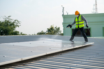 Maintenance technician using high pressure water to clean the solar panels that are dirty with dust...