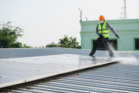 Maintenance Technician Using High Pressure Water To Clean The Solar Panels That Are Dirty With Dust To Improve The Efficiency Of Solar Energy Storage.