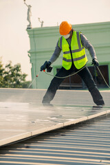 Maintenance technician using high pressure water to clean the solar panels that are dirty with dust to improve the efficiency of solar energy storage.