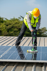 Maintenance technician using cleaning mop and to clean the solar panels that are dirty with dust to...