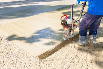 Worker is using power tool with engine, compactor, for level and compact fresh concrete