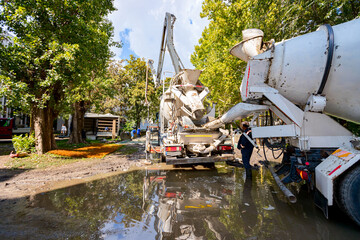 Concrete mixer at the construction site, pouring concrete from one mixer to other with pump for...