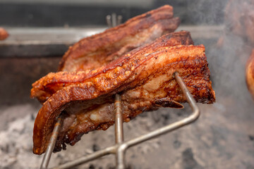 Several pieces of Liempo, or pork belly skewered on a rolling spit and roasted on an oven at a roadside restaurant.
