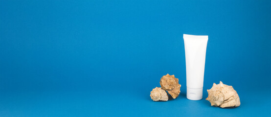 Cosmetic tube and whelk seashells on blue background, banner. Concept of beauty products based on marine-derived ingredients