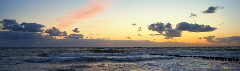 Sea coastline with waves. Baltic sea against dramatic cloudy sky at sunset. Panoramic nature landscape
