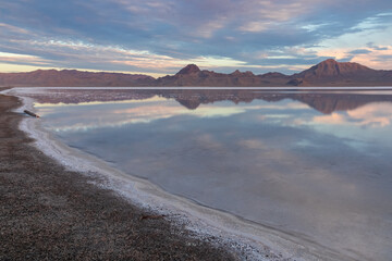 Scenic view of beautiful mountains reflecting in lake of Bonneville Salt Flats at sunrise, Wendover, Western Utah, USA, America. Looking at summits of Silver Island Mountain range. Romantic atmosphere