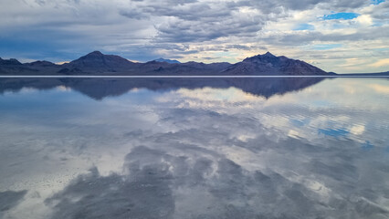 Fototapeta premium Scenic view of beautiful mountains reflecting in lake of Bonneville Salt Flats at sunset, Wendover, Western Utah, USA, America. Looking at summits of Silver Island Mountain range. Romantic atmosphere