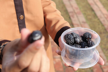 Close up of male hand holding date fruits with plastic food containers. Selective focus image