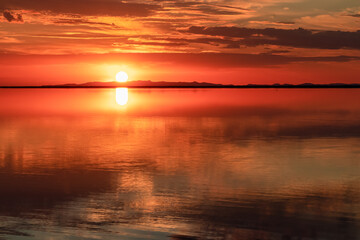 Naklejka premium Scenic sunrise view of beautiful water reflections in lake of Bonneville Salt Flats, Wendover, Western Utah, USA, America. Dreamy clouds mirroring on the water surface creating romantic atmosphere