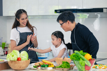 Child playing cook food with father and mother at home kitchen. Asian family happiness moment together.