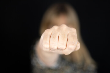 Woman with closed fist to campaign against gender violence and pain. Hand raised and punch to stop and dissuade for self harm awareness, stop abusing, bullying, mental health. Copy space.