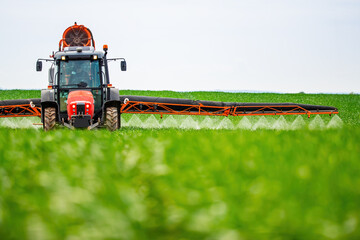 Tractor-applied herbicides, pesticides, and fungicides in wheat fields, farmer protecting crops...