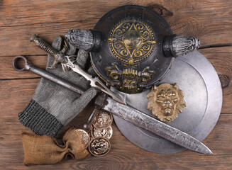 Knight armor, sword, helmet and shield on wooden background