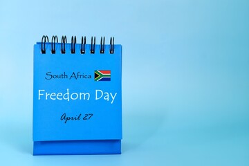 April 27 as South Africa Freedom Day date reminder on blue desk calendar with flag icon. National day celebration concept.