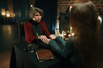 Young woman at fortune teller chiromancer consultation side view shot