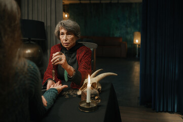 Mature witch using crystal pendulum to predict future for client