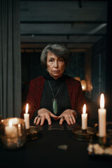 Portrait of fortune teller holding crystal pendant for divination seance