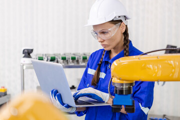 female technician engineer using laptop checking automation robotics at industrial modern factory. woman working at factory innovation automation robot.