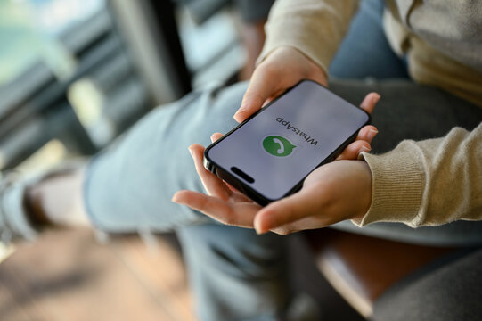 Close-up image of an Asian woman using WhatsApp mobile application to chat with her friends
