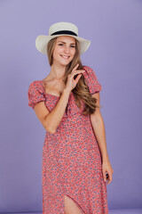 beautiful blonde woman in a white hat stands on a purple background