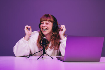Happy woman recording a podcast in a studio - obrazy, fototapety, plakaty