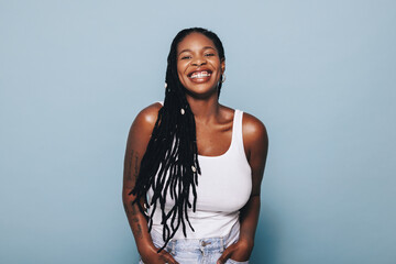Happy young black woman smiling at the camera while standing in a studio in casual clothing