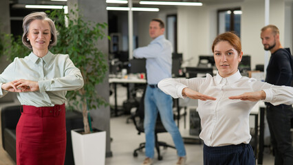 Obraz premium Four office workers warm up during a break. Employees do fitness exercises at the workplace. 