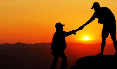 silhouette of lovers holding hand together on hill under sunset sky background