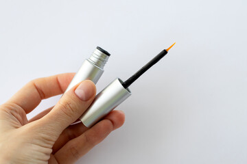 Eyebrow Serum for Women. Thin brush serum in a girl's hand with essential oils and peptides on her eyebrows for strong growth, density and problem solving. Close-up.