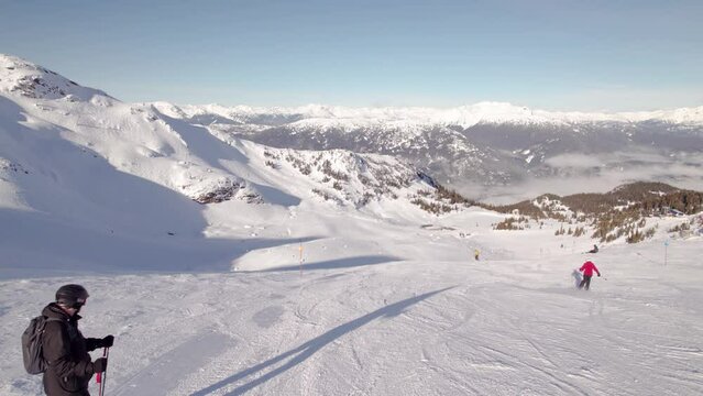 Skier overlooking breathtaking mountain vista, ski mountain, sunny day, winter, ski hill. 4k 24fps