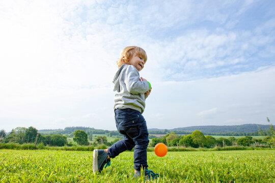 a little boy playing balls and having fun on a green field in the country side, Caurel Brittany, France.